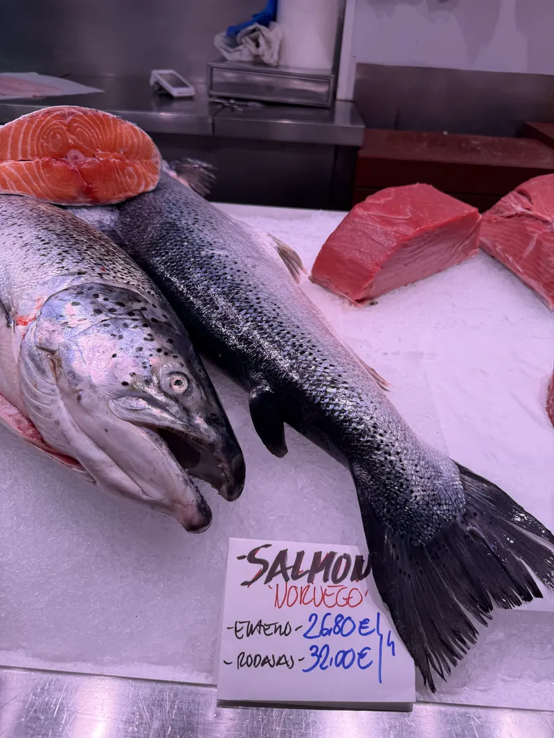 Salmón noruego entero y en rodajas sobre hielo, con su cartel escrito a mano